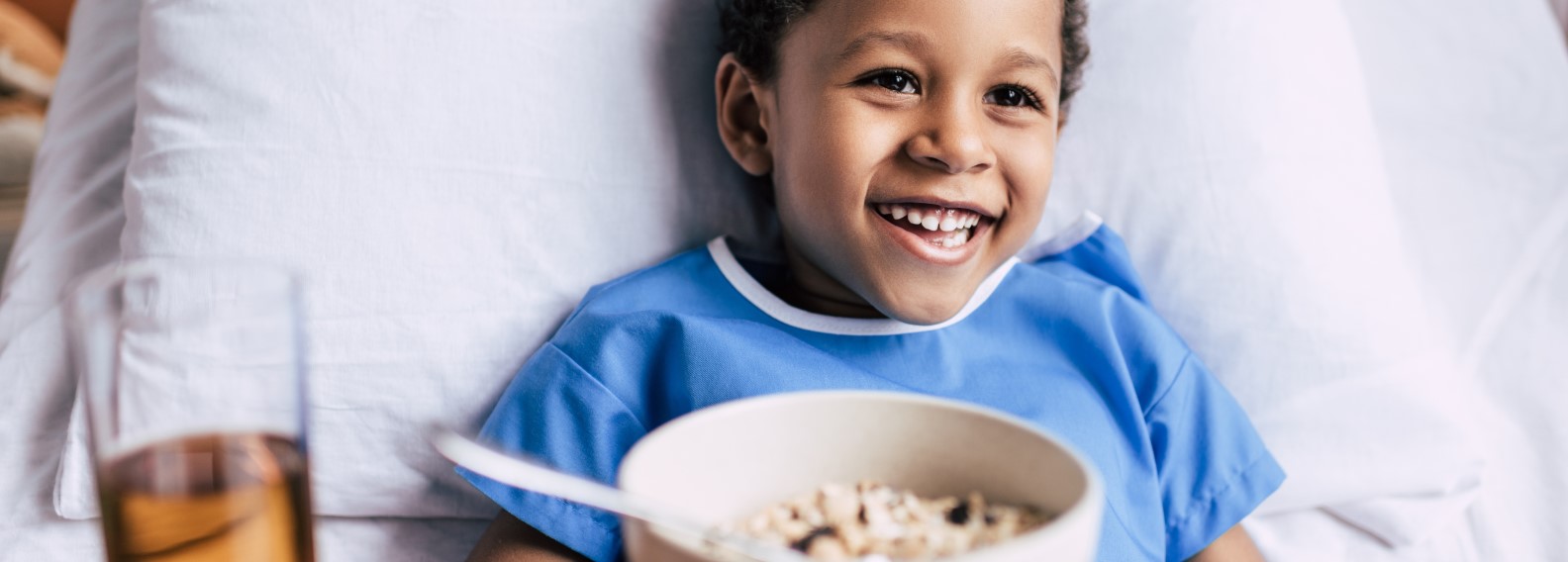 Child in a hospital bed eating and smiling