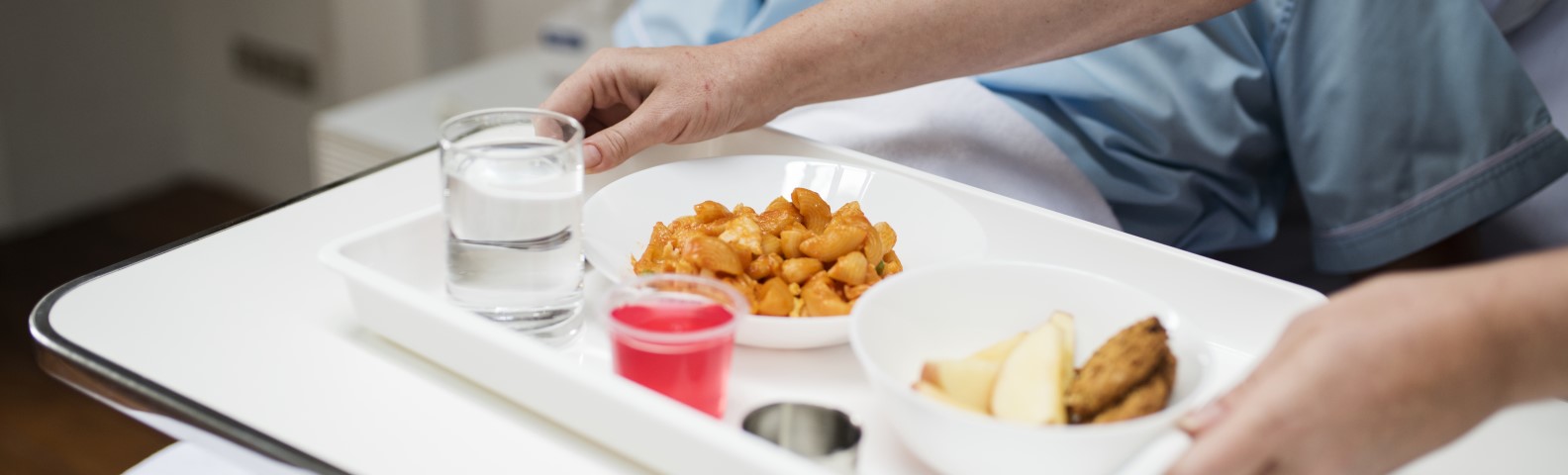 Tray with a variety of food and drinks placed on a bed, part of the Patient Meal Service