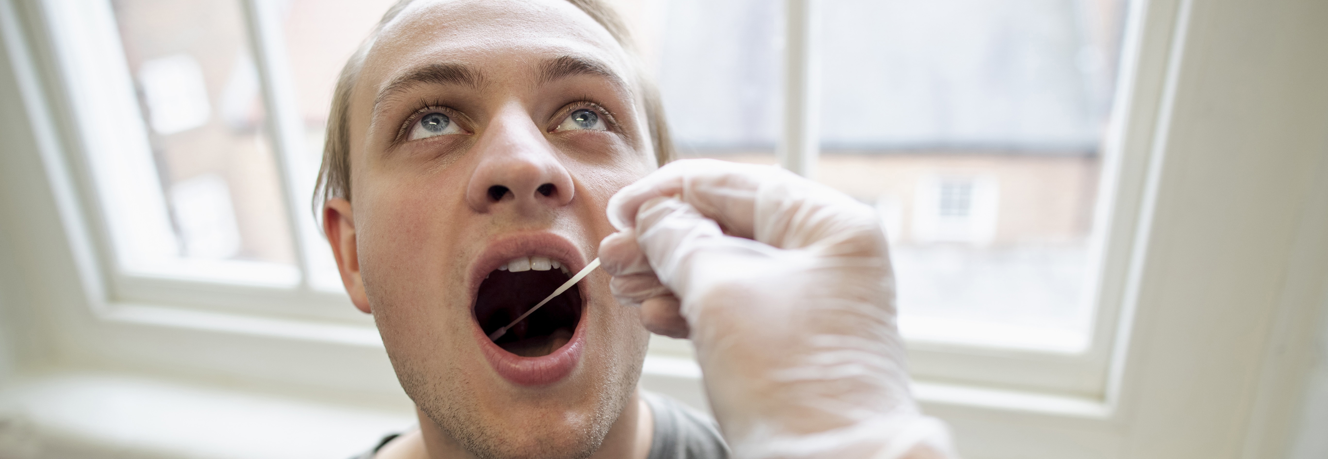 Man with open mouth having covid swab