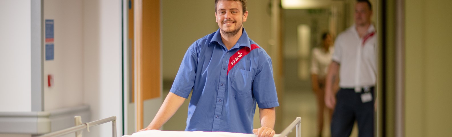 man pushing a stretcher in a hallway and smiling