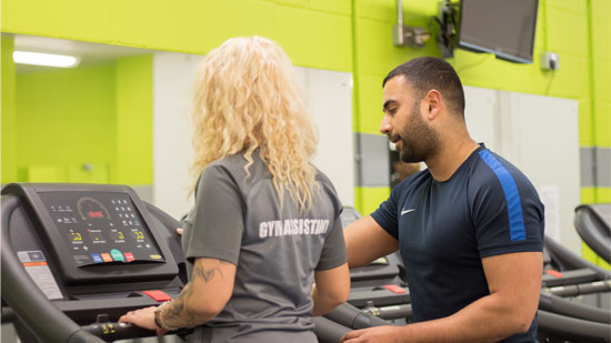 Gym instructor and assistant stood at treadmill