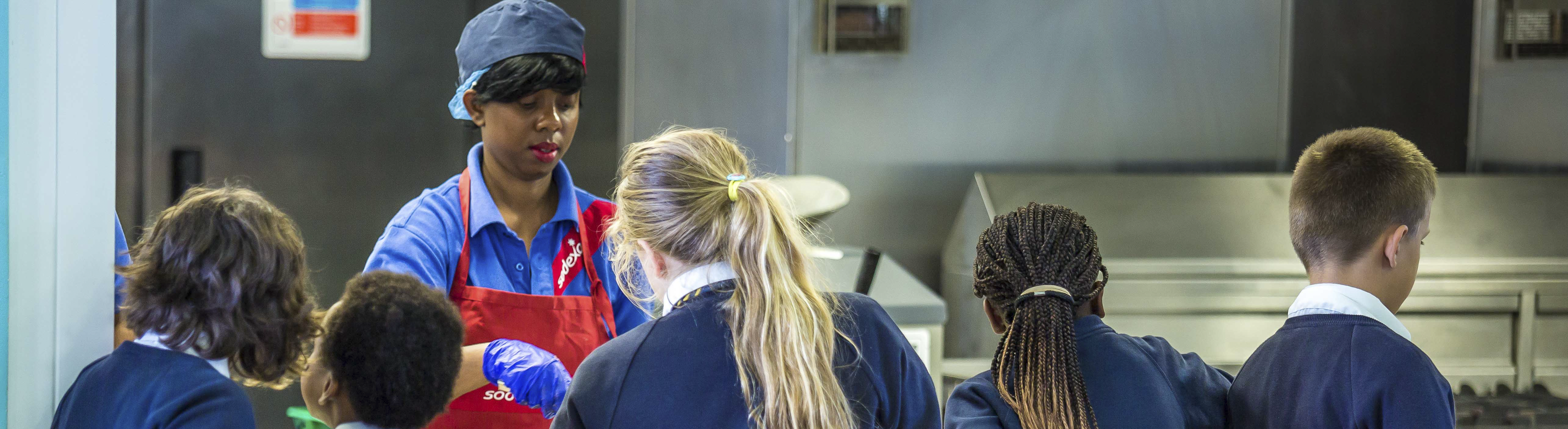 A Sodexo employee handing out food to students at the lunch counter
