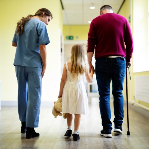 kid with dad and a nurse on hospital hall