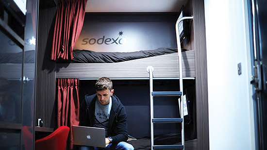 A man working on a bunk looking at his laptop